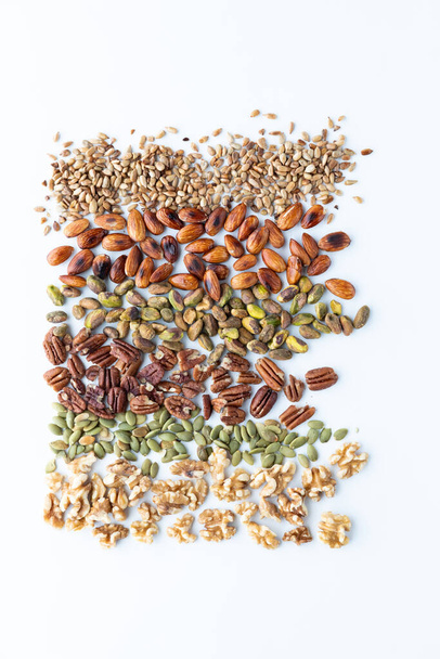 Top down view of rows of various nuts and seeds against a white background. - Foto, Bild