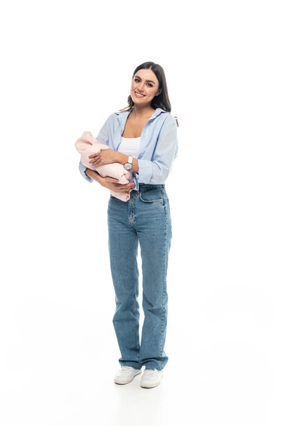full length view of young woman with newborn child smiling at camera on white background - Photo, image
