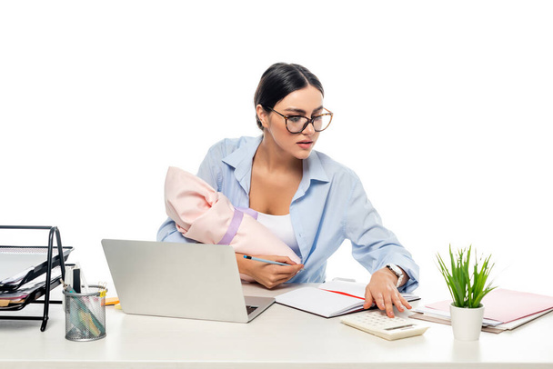 fiatal anya gazdaság újszülött baba, miközben dolgozik közelében laptop elszigetelt fehér - Fotó, kép