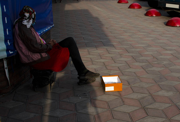 Uma mulher mendigo com uma caixa de esmolas de papel. - Foto, Imagem