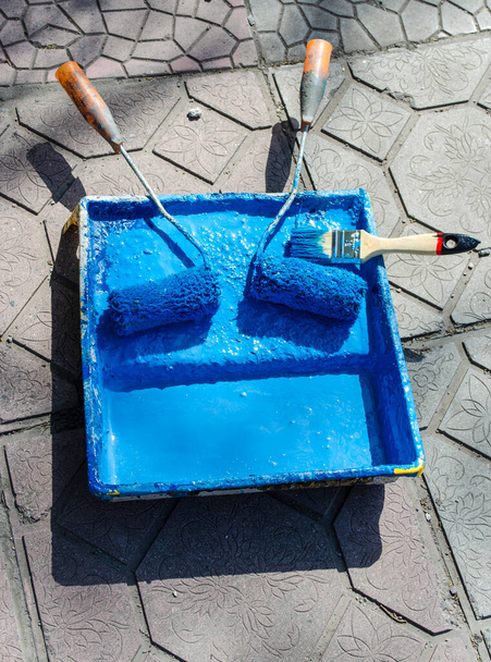 Een roller met blauwe verf in de lade. - Foto, afbeelding