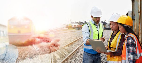 Skuteczni specjaliści ds. logistyki kolejowej lub inżynierowie kolejowi w kaskach i kamizelkach bezpieczeństwa przeprowadzają inspekcje i realizują plan prac dotyczący zarządzania pociągiem towarowym na torach kolejowych.. - Zdjęcie, obraz