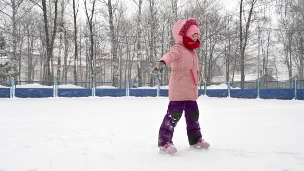 Pieni tyttö vaaleanpunainen takki opettelee luistella - Materiaali, video