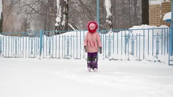 Девочка в розовой куртке учится кататься на коньках - Кадры, видео