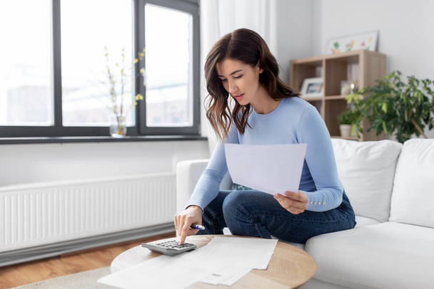 woman with papers and calculator at home - Foto, Bild