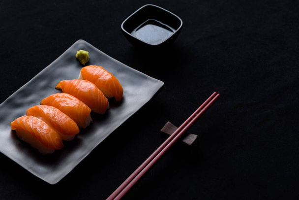 Salmon sushi with green wasabi on Black plate or dish and shoyu sauce on black background - Photo, Image