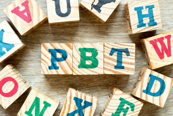 Alfabeto letra bloque en la palabra PBT (Abreviatura de Beneficio antes de impuestos) con otro sobre fondo de madera - Foto, imagen