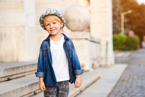 Happy child walking the city street. Cute boy wearing stylish summer outfit. Child with positive emotions. Kids summer fashion. Happy and healthy childhood. - Foto, imagen