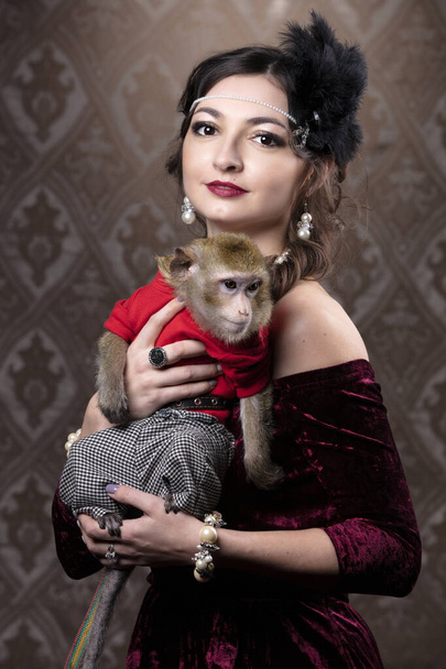 Retrô retrato feminino no estilo de 20 ou 30 anos. Uma senhora linda está segurando um macaquinho. - Foto, Imagem