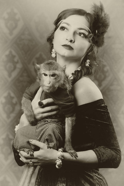 Retrato femenino retro en el estilo de los años 20 o 30. Una hermosa dama sostiene a un pequeño mono. Foto en estilo vintage. - Foto, Imagen