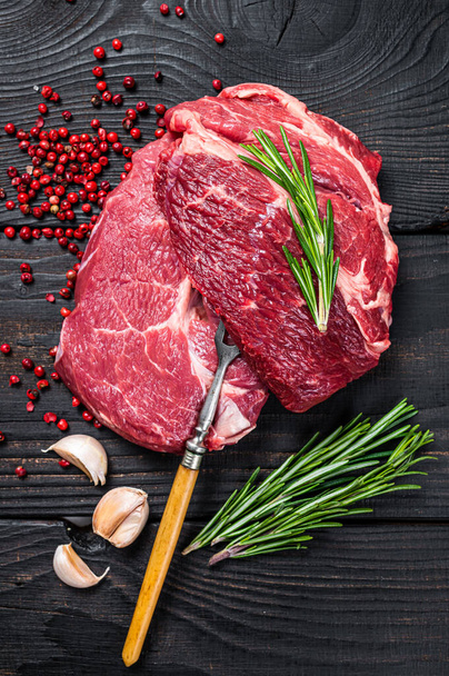 Fresh Raw Chuck eye roll beef steak on butcher table. Black wooden background. Top view - Фото, изображение