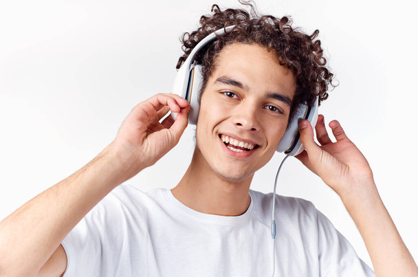 Kıvırcık saçlı ve kulaklıklı bir adam müzik dinliyor. Yüksek kalite fotoğraf - Fotoğraf, Görsel