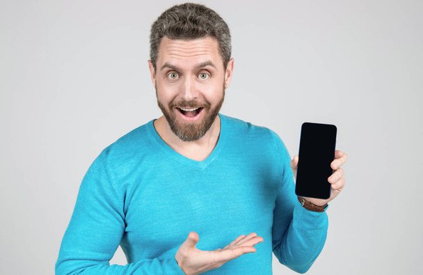 glücklicher Mann mit Bart demonstriert Smartphone, Promotion. - Foto, Bild
