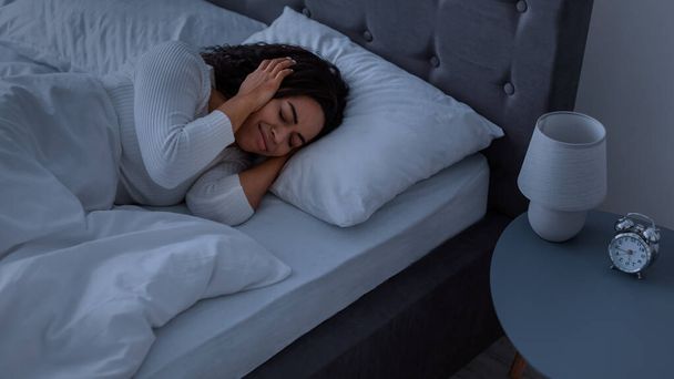 Mujer negra estresada cubriendo orejas acostadas en la cama - Foto, imagen