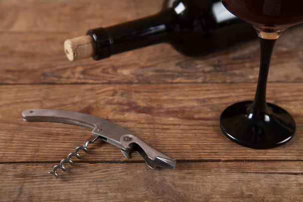 Μπουκάλι, γυάλινο και κρασί με τιρμπουσόν σε ξύλινο φόντο.  - Φωτογραφία, εικόνα