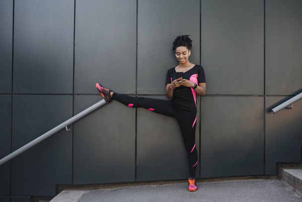 Young fitness woman runner stretching legs before city jog - Foto, Bild