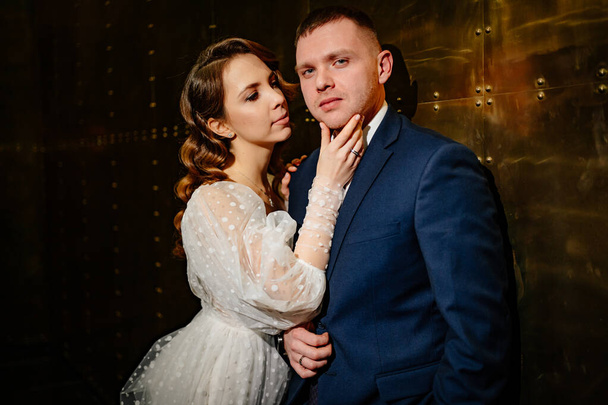 bridegroom and bride in a elegant dress in a dark corridor - Fotó, kép
