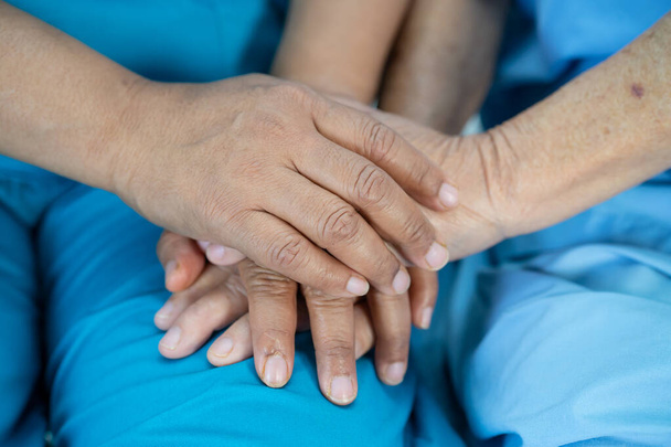 Держать за руки азиатскую пожилую женщину старшего возраста или пожилую женщину пациентку с любовью, уходом, поощрением и сочувствием в стационарном отделении, здоровый сильный медицинский концепт - Фото, изображение