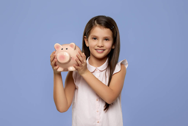smiling child girl holding pink piggy bank - 写真・画像
