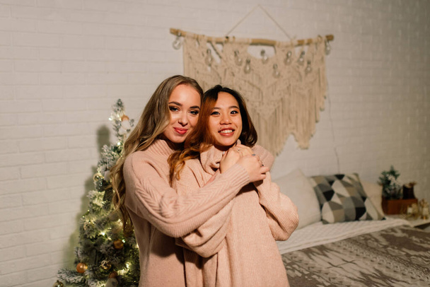Dos mujeres asiáticas jóvenes sonriendo con felicidad en la fiesta de Navidad, pareja lgbt, celebración - Foto, imagen