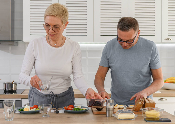 Zamknij się w średnim wieku para gotowanie zdrowe jedzenie razem - Zdjęcie, obraz