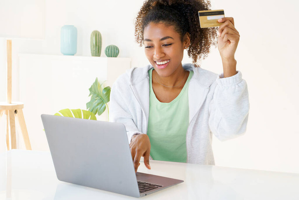 Sonriente joven mujer negra con tarjeta de crédito de compras desde casa - Foto, imagen