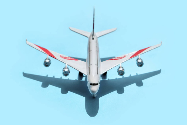 vooraanzicht van Speelgoedvliegtuig op blauw papieren achtergrond, close-up. concept van luchtvervoer, toerisme, reizen. - Foto, afbeelding
