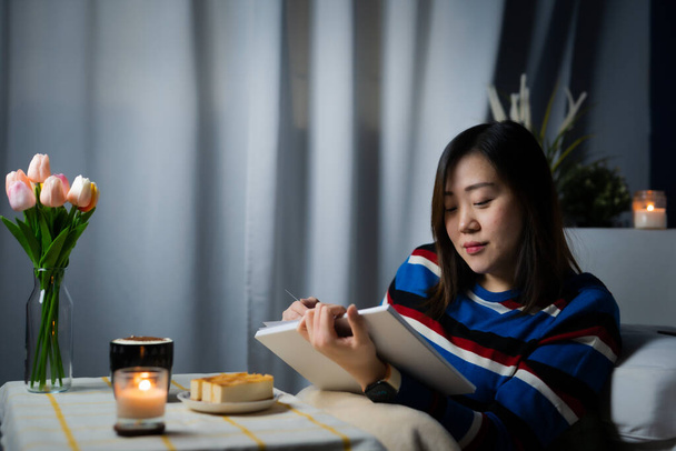 азиатская женщина работает из дома и расслабиться, читая книгу во время карантина стадии - Фото, изображение