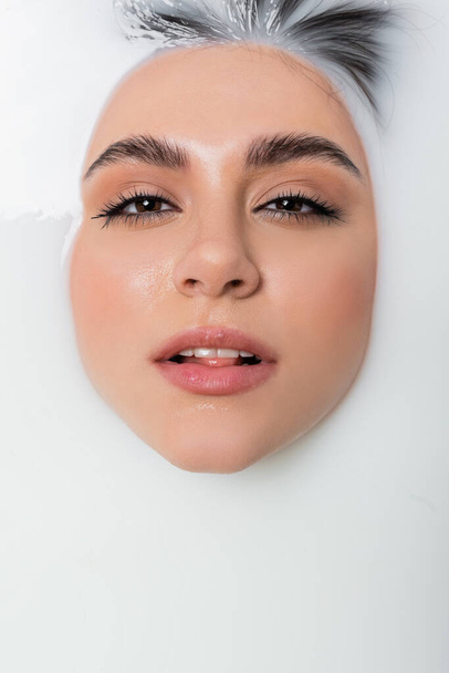 close up view of face of seductive woman bathing in milk - Фото, изображение