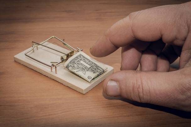 El hombre trata de robar un billete de un dólar de una trampa para ratones - Foto, Imagen