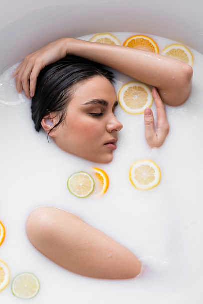 young woman bathing in milk with fresh, sliced citruses - Photo, Image