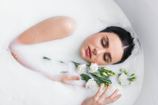 красива жінка розслабляється в молочній ванні з квітами еустоми
 - Фото, зображення