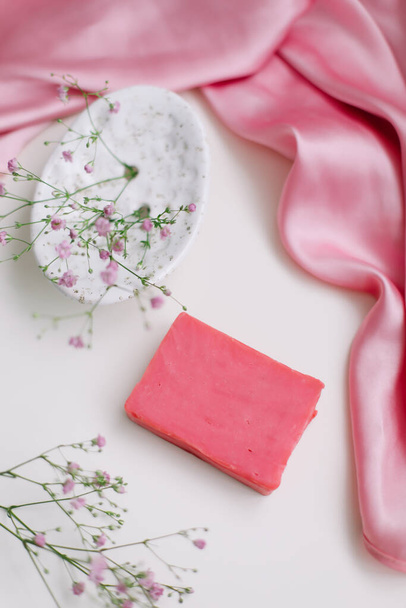 Spa composition with pink soap bar with ceramic soap dish, silk babric and flowers - Foto, Imagem