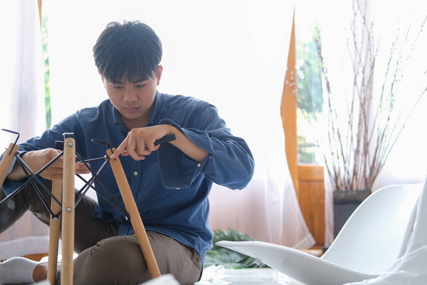 Junger Mann bastelt, baut Möbel zu Hause zusammen - Foto, Bild