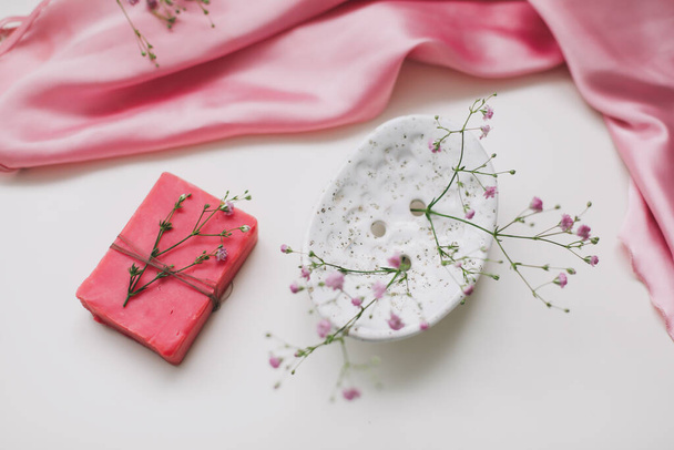 Spa-Komposition mit rosa Seifenstab mit Keramik-Seifenschale, Seidenbabric und Blumen - Foto, Bild