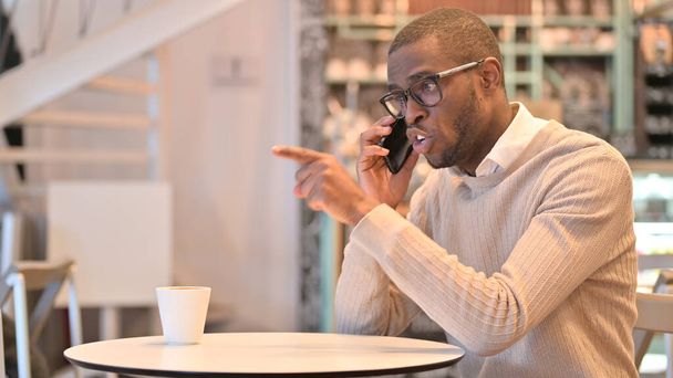 Dühös afrikai férfi dühös Smartphone a Cafe  - Fotó, kép