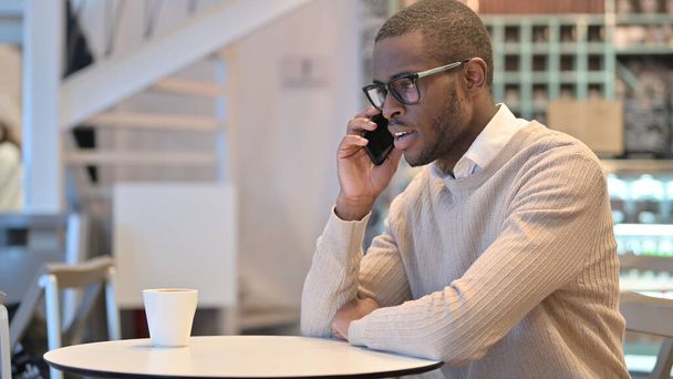Atraktivní africký muž mluví na telefonu v kavárně  - Fotografie, Obrázek