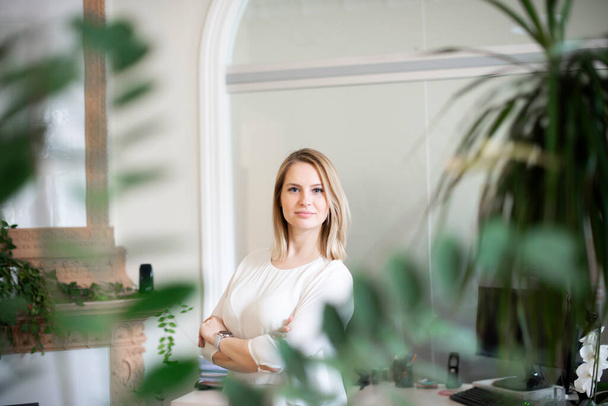 Портрет молодої бізнес-леді в білій блузці, стоячи в офісі і дивлячись на камеру
 - Фото, зображення