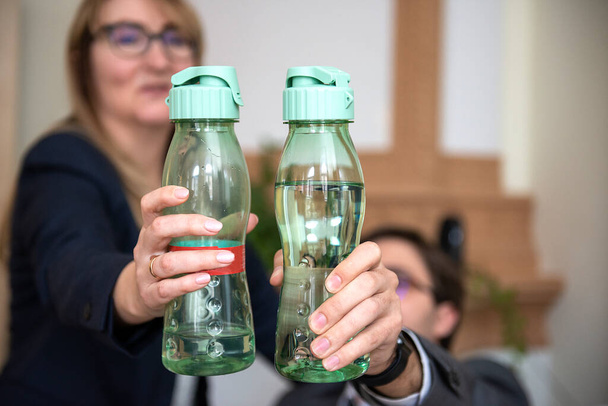 Közelkép két üzletember kezét kezében műanyag ásványvíz palackok, egészséges életmód, víz ivás koncepció - Fotó, kép