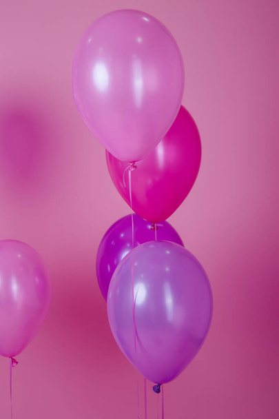 επιπλέουν πολύχρωμα ροζ μπαλόνια κόμμα σε ροζ παστέλ φόντο. Χώρος για κείμενο. Ελάχιστη ιδέα δημιουργική έννοια της ευτυχίας, χαρά, γενέθλια. διακοπές web banner με αντίγραφο χώρο. - Φωτογραφία, εικόνα