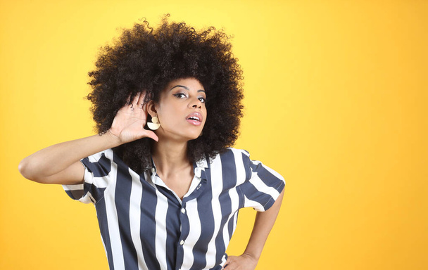 mixed afro woman, with hearing problems, hand on ear yellow background - Фото, зображення