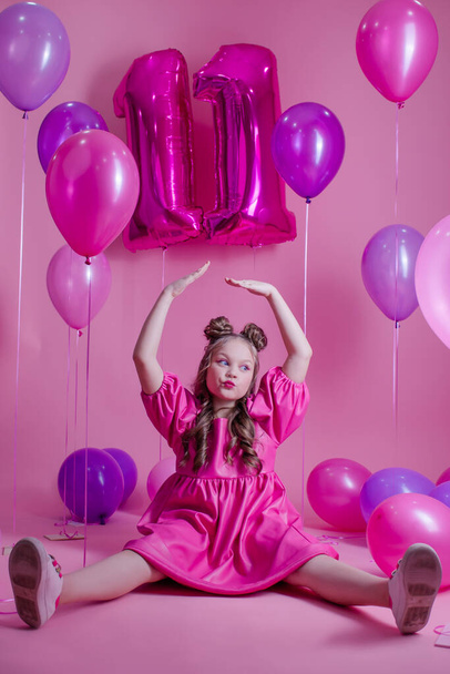 menina morena doce com rosa compõem e no vestido de couro rosa. perto de balões coloridos em forma de número onze. no fundo cor-de-rosa. Conceito de alegria, festa, celebração de aniversário - Foto, Imagem