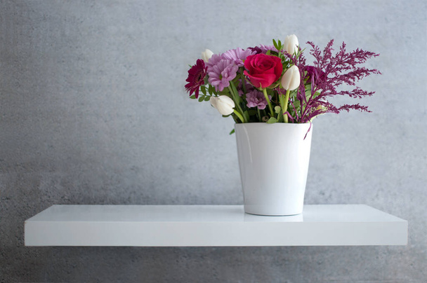 Spring flowers on floating white shelf against concrete wall - Foto, Bild