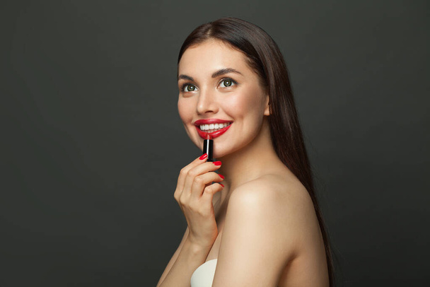 Junge schöne glückliche Frau mit roten Lippen Make-up und Lippenstift auf schwarzem Hintergrund - Foto, Bild