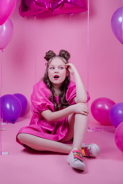attractive brunette girl model with pink make up and in pink leather dress near colorful balloons on pink background.concept of joy, party, birthday - Φωτογραφία, εικόνα