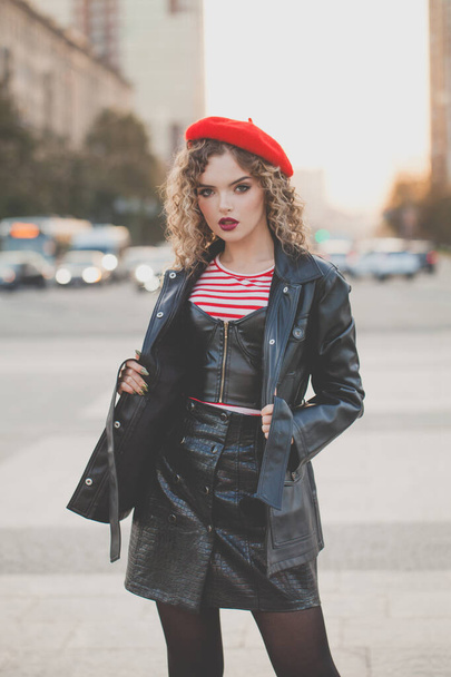 Junge stylische Frau in schwarzer Jacke und roter Baskenmütze auf der Straße  - Foto, Bild
