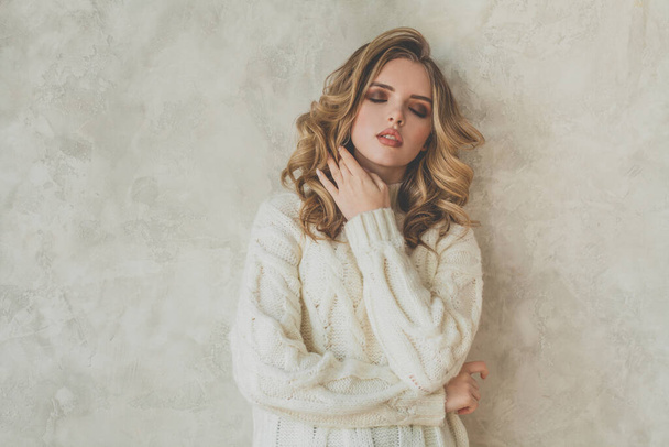Nice woman with healthy curly hair in white sweater posing on gray background - Φωτογραφία, εικόνα