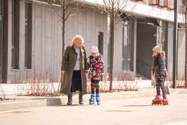 grandma teaches two granddaughters to roller skate - Photo, Image