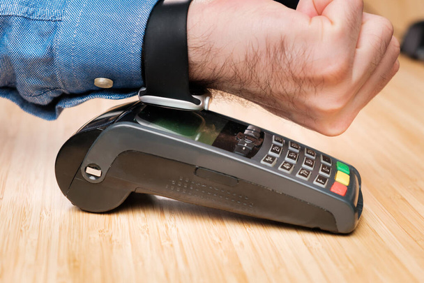 Клієнт платить за допомогою смарттексу з використанням технології NFC. Безтактний платіжний термінал. - Фото, зображення