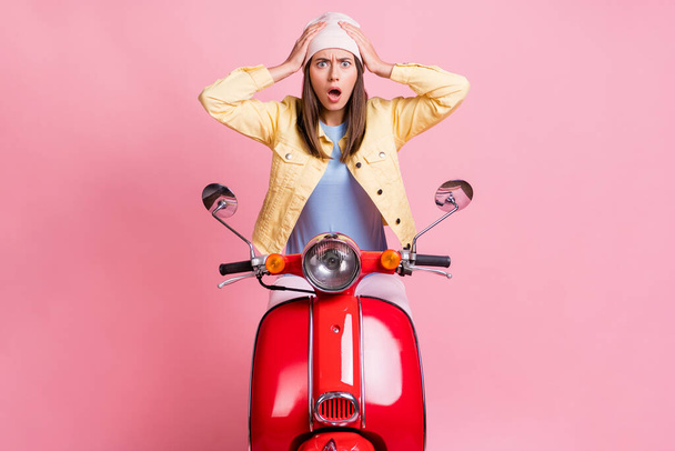 Photo of young shocked hear bad news attractive woman girl female hold hands head ride red motorbike isolated on pink color background - Φωτογραφία, εικόνα